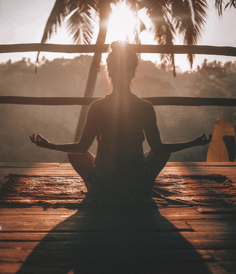 Meditation practice — person in seated meditation surrounded by plants and natural light